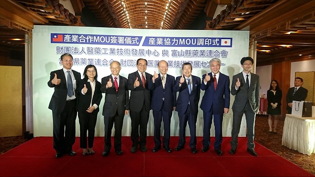 圖：財團法人醫藥工業技術發展中心與富山縣藥業連合會產業合作MOU簽署儀式紀念合影（左起TJPO執行長呂正欽 [經濟部工業局副組長]、經濟部工業局李佳峯科長、藥技中心蘇慕寰董事長、經濟部工業局呂正華局長、富山縣石井隆一知事、富山藥連中井敏郎會長、富山藥連高田吉弘專務理事、富山縣厚生部藥政策課塩川智規課長）